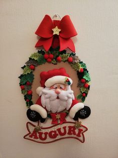 a santa clause hanging on the side of a wall with a wreath and ribbon around it