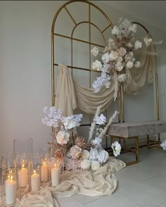 a table topped with lots of white flowers and lit candles next to a gold frame