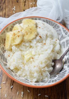 a bowl filled with rice and bananas on top of a wooden table next to a napkin