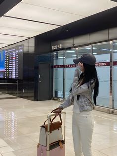 a woman standing in an airport with her luggage