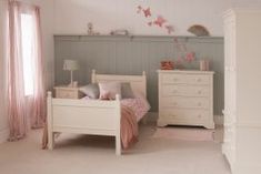 a child's bedroom with white furniture and pink curtains