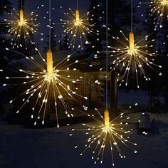 fireworks are lit up in the night sky above snow covered ground and trees, with lights hanging from them