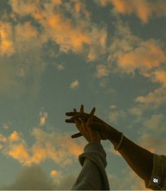 two hands reaching up into the sky with clouds in the background