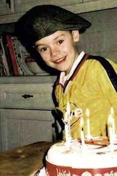 a young boy sitting in front of a cake with lit candles on top of it