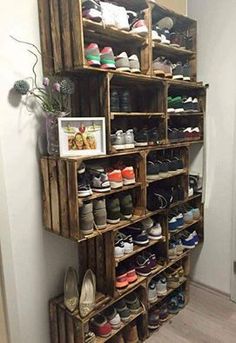 a wooden shoe rack filled with lots of pairs of shoes next to a white wall