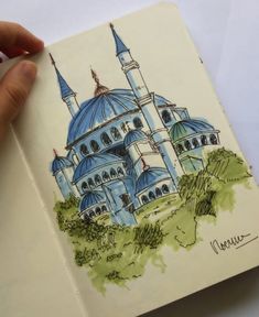 a drawing of a blue mosque in the middle of someone's hand, with trees and bushes around it