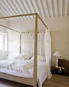 a white bed sitting in a bedroom next to a window