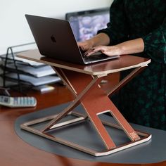 a woman using a laptop computer on top of a wooden table