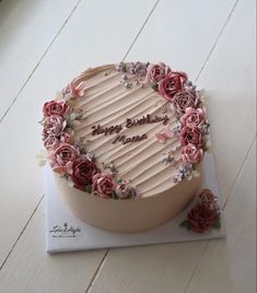 a birthday cake decorated with pink roses on top of a table