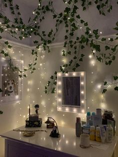 a vanity with lights and plants on the wall above it, along with other items