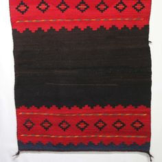 a red, black and brown rug on a white background with an orange stripe in the middle