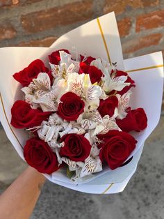 a bouquet of red roses and white orchids in someone's hand on the street