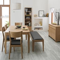 a dining room with white walls and wooden furniture in the center, along with an open bookcase