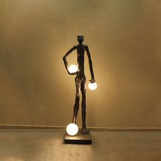 a bronze statue holding two light bulbs in it's hands and standing on top of a table