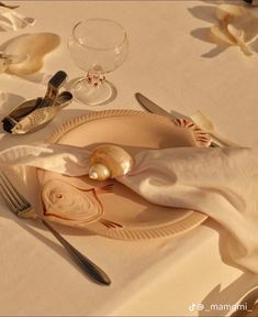 the table is set with an empty plate, silverware and seashells on it