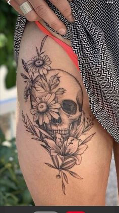 a woman's thigh with a skull and flowers on it