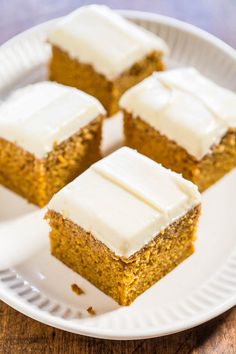 four pieces of pumpkin cake on a white plate with frosting sitting on top of it