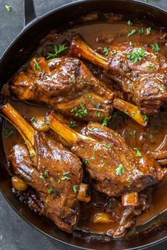 a skillet filled with meat and vegetables covered in gravy, garnished with parsley