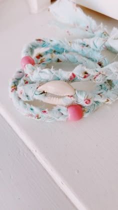 two bracelets with seashells on them sitting on top of a white table