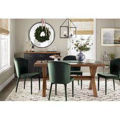 a dining room table with green chairs and a wreath hanging on the wall above it