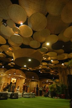 people are standing in the middle of a room with wicker baskets hanging from the ceiling