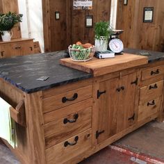 a kitchen island made out of wood with black granite counter top and drawers on each side