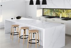 a kitchen with marble counter tops and stools next to an island in the middle