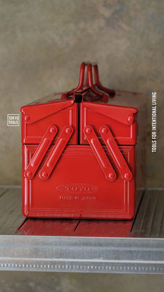 a red plastic box sitting on top of a shelf next to a metal container with handles