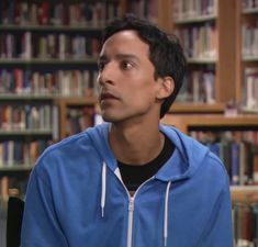 the young man is sitting in front of bookshelves