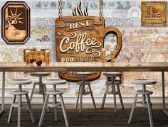 a wooden table topped with white stools next to a wall covered in coffee signs