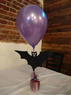 a purple balloon with a bat on it is sitting in a glass vase next to a brick wall