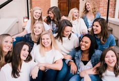 a group of young women sitting on the steps laughing and posing for a photo together