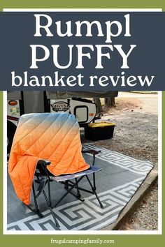 an orange and black blanket sitting on top of a chair in front of a camper