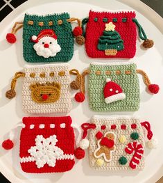 four crocheted christmas purses sitting on top of a white plate