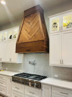 a stove top oven sitting inside of a kitchen next to white cupboards and drawers