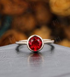 a close up of a ring with a red stone in the center on a table