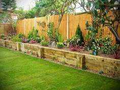 a garden area with wooden fence and green grass