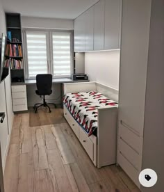 a room with a bed, desk and bookcases on the wall in it