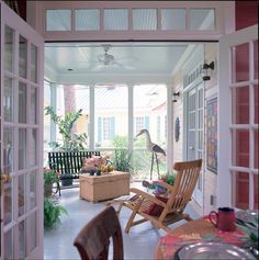 an open porch with chairs and flowers on the table