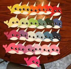 a wooden table topped with lots of different colored narwhales on top of it