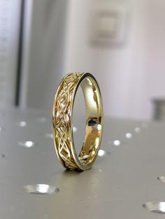 two gold wedding rings sitting on top of a table next to each other and one has an intricate design in the middle