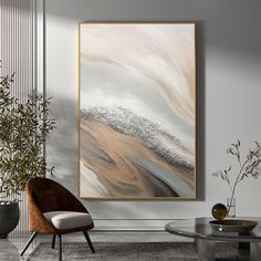 an abstract painting hangs on the wall above a chair and table in a modern living room