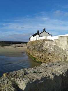 there is a building on the side of the water and rocks in front of it