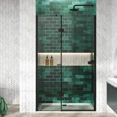 a bathroom with green tiles on the walls, and a glass shower door in the middle