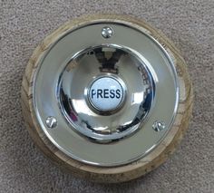 a metal object with the word press on it's center piece and wood base