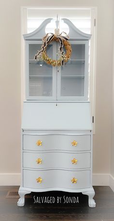 a white dresser with a wreath on top and the words salvaged by sonda above it