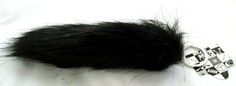 a black furry animal tail laying on top of a white sheet