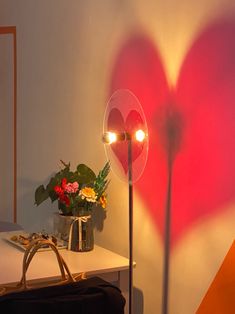 a heart - shaped light is shining on the wall next to a purse and flower pot