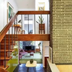 a living room with stairs leading up to the second floor and a dining table in front of it