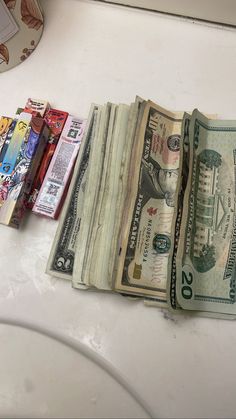 several stacks of money sitting on top of a white counter next to a clock and other items